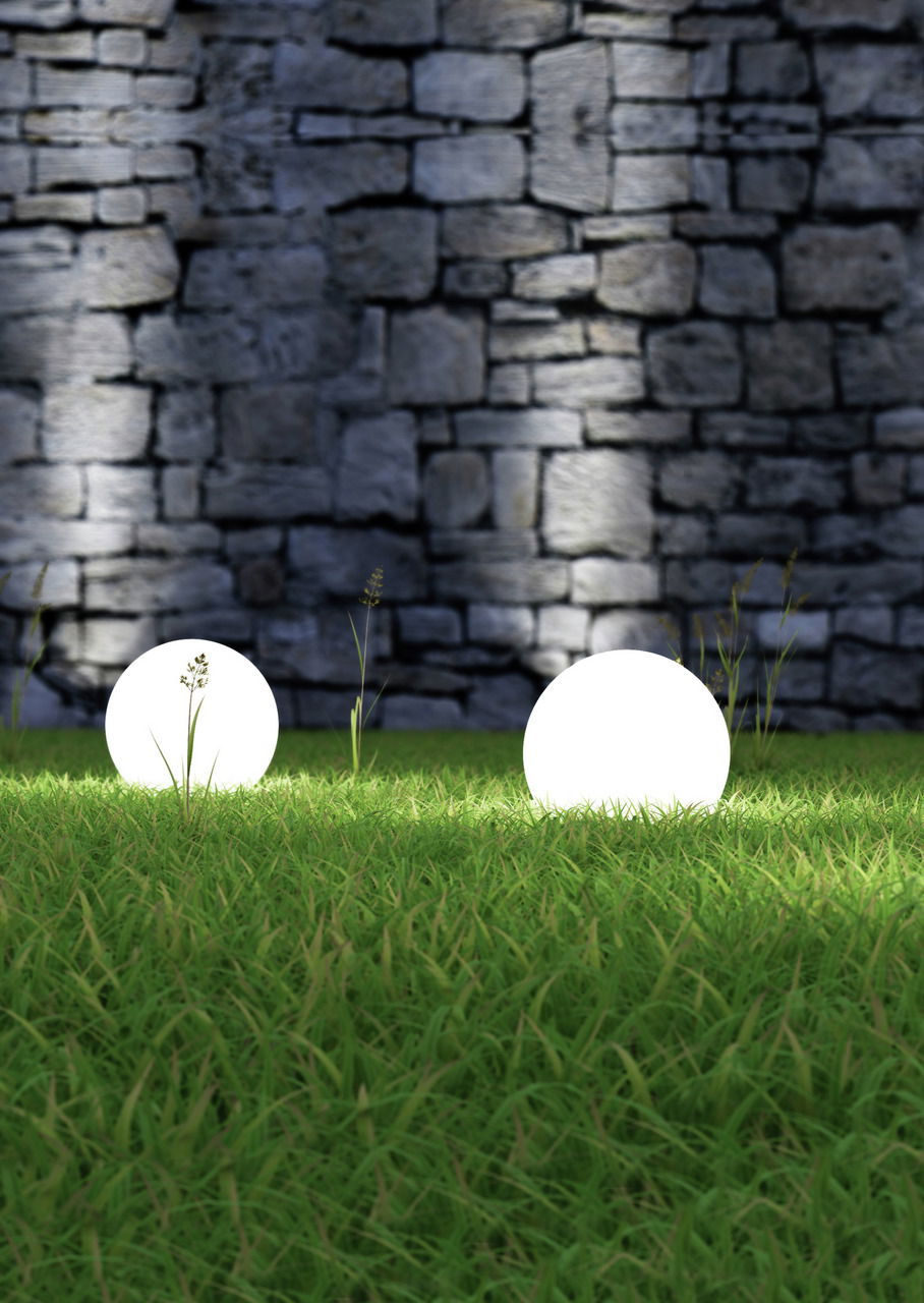 Reality Leuchten Gartenleuchte BOLO Zwei leuchtende Kugeln auf einer grünen Wiese vor einer Steinmauer, seitliche Perspektive.