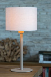 Zylindrischer Lampenschirm in hellem Stoff auf einem Tisch, seitliche Perspektive