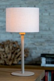 Zylindrischer Lampenschirm in hellem Stoff auf einem Tisch, seitliche Perspektive