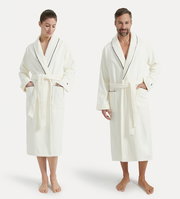 Zwei Personen tragen weiße Bademäntel mit Schalkragen und schwarzer Paspelierung, frontal fotografiert.