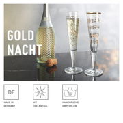 Zwei elegante Champagnergläser mit goldenen Verzierungen, eines mit geometrischem Muster und das andere mit Notenlinien, auf einem Tisch neben einer Sektflasche, seitliche Perspektive.