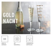 Zwei elegante Champagnergläser mit goldenen Verzierungen, eines mit geometrischem Muster und das andere mit Notenlinien, auf einem Tisch neben einer Sektflasche, seitliche Perspektive.
