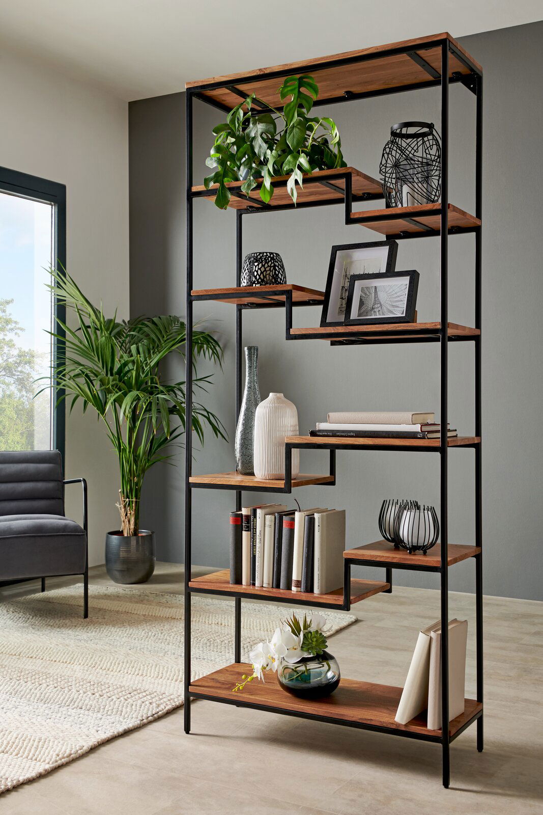 Modernes Regal mit schwarzem Metallrahmen und Holzböden, dekoriert mit Pflanzen, Büchern und Vasen, seitliche Perspektive.