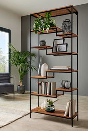 Modernes Regal mit schwarzem Metallrahmen und Holzböden, dekoriert mit Pflanzen, Büchern und Vasen, seitliche Perspektive.