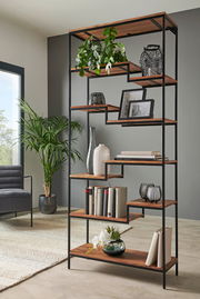 Modernes Regal mit schwarzem Metallrahmen und Holzböden, dekoriert mit Pflanzen, Büchern und Vasen, seitliche Perspektive.