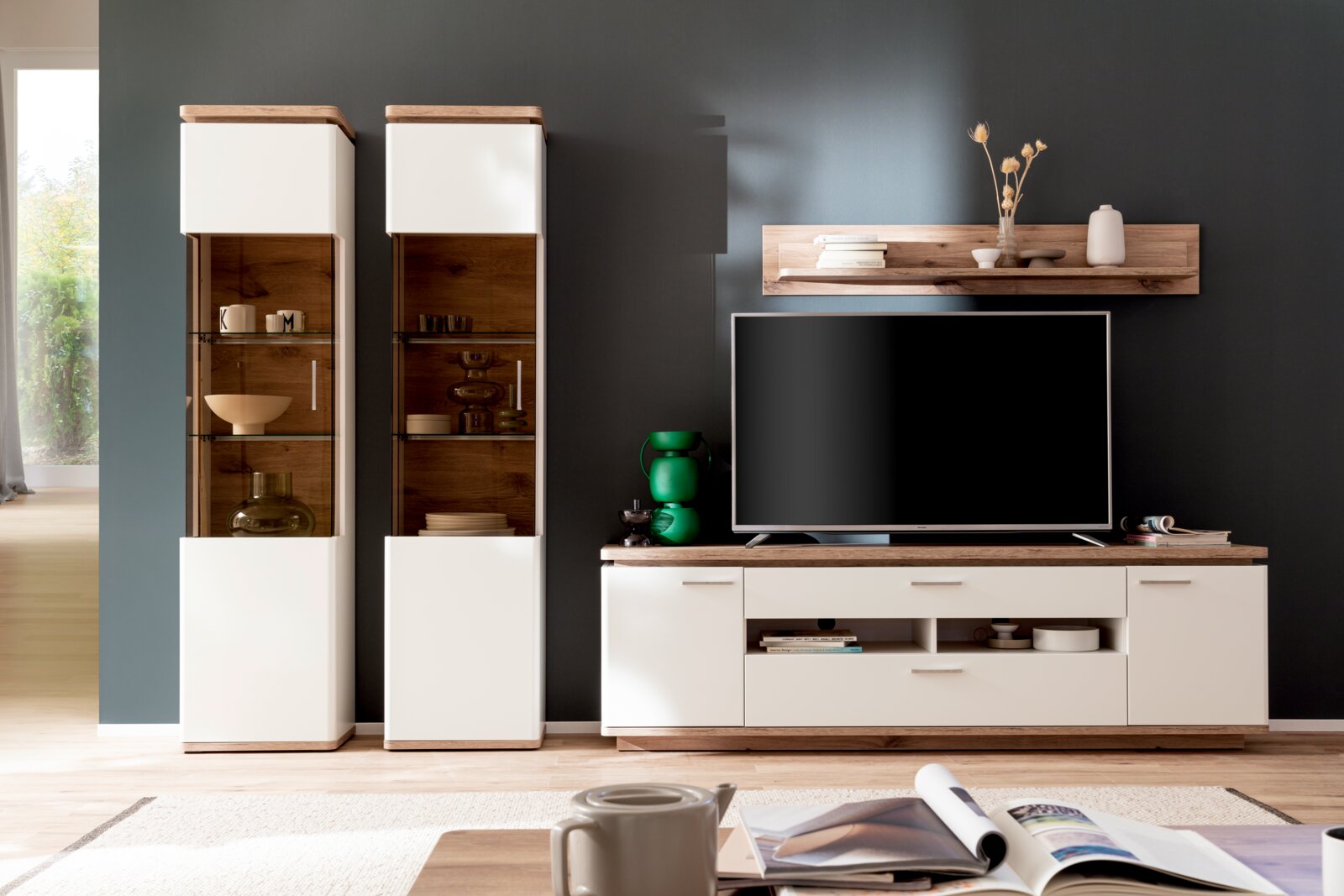 Stylife Vitrine PALERMO Modernes Wohnzimmer-Entertainment-Set in Weiß und Holzoptik mit zwei Vitrinenschränken, TV-Lowboard und Wandregal vor dunkelgrauer Wand, Frontansicht auf Augenhöhe.