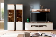 Moderne entertainmentset voor de woonkamer in wit en houtlook, bestaande uit twee vitrinekasten, een tv-lowboard en een wandrek tegen een donkergrijze muur, vooraanzicht op ooghoogte.