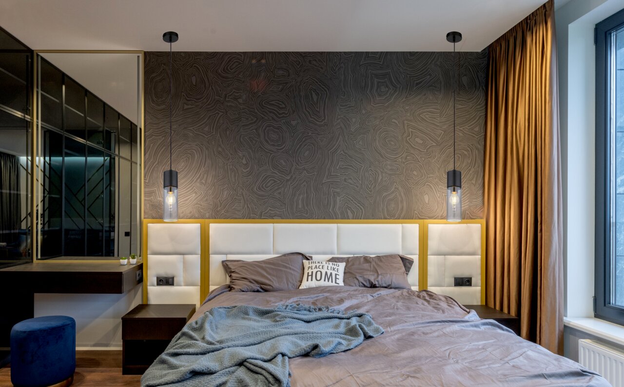 Moderne Hängeleuchte aus schwarzem Metall über einem Bett, seitliche Perspektive