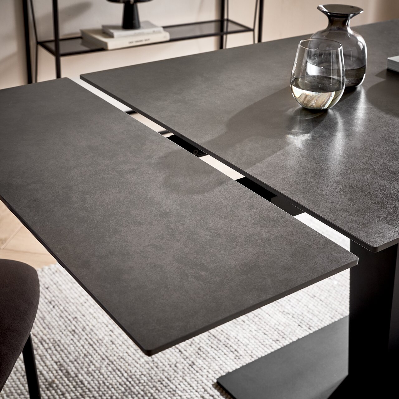 Moderne eettafel met donker, uitschuifbaar tafelblad, gezien vanuit vogelperspectief.