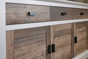 Close-up van een dressoir met houtlook en zwarte handgrepen, gezien van voren.