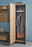 Voleo Garderobenschrank FLASH Garderobenschrank aus Holz mit geöffneter Tür, zeigt Innenraum mit Kleiderstange, Mantel und Hut, seitliche Perspektive