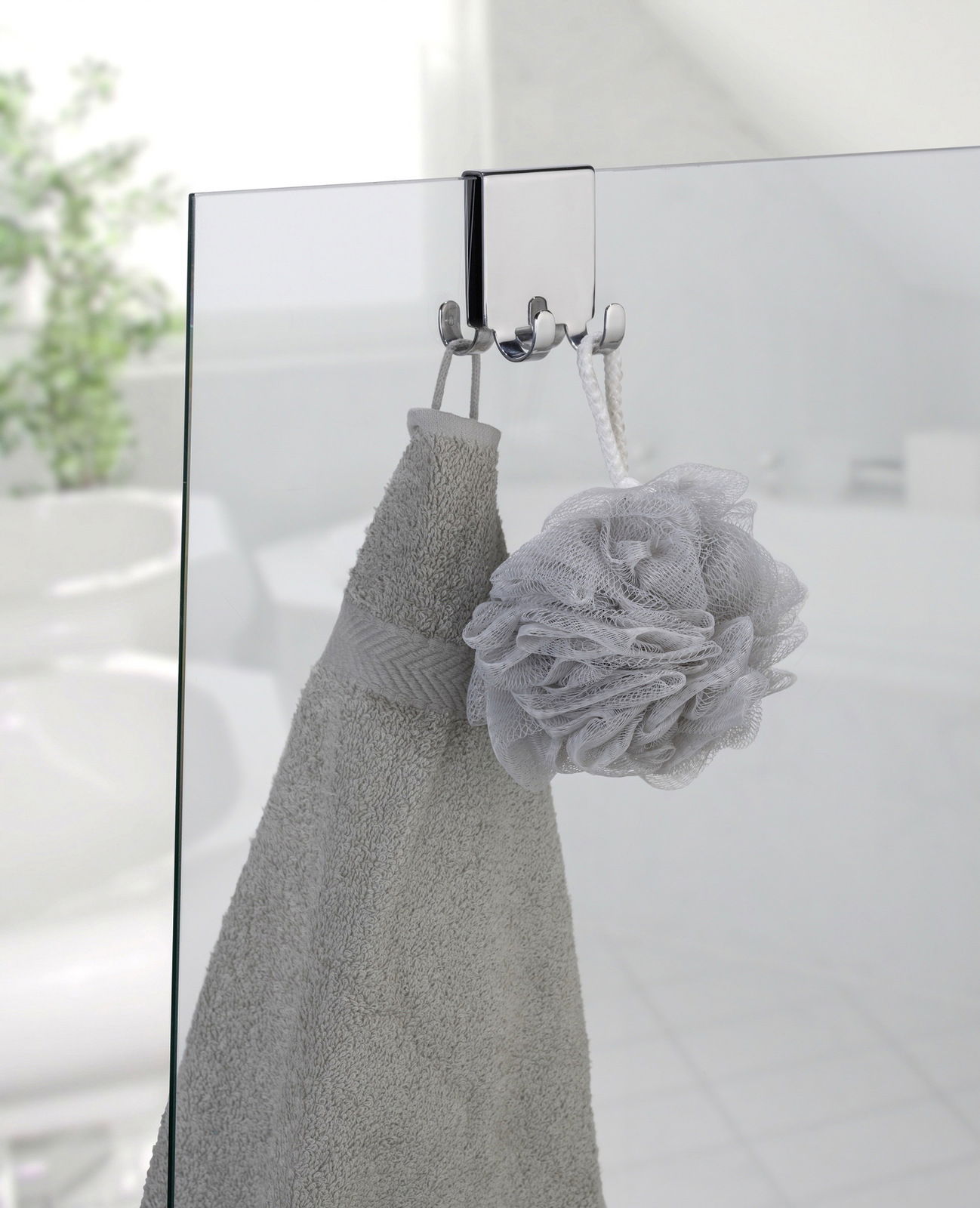 Edelstahl Doppel-Duschhaken an einer Glastür, von vorne betrachtet, mit einem Handtuch und einem Duschschwamm aufgehängt.