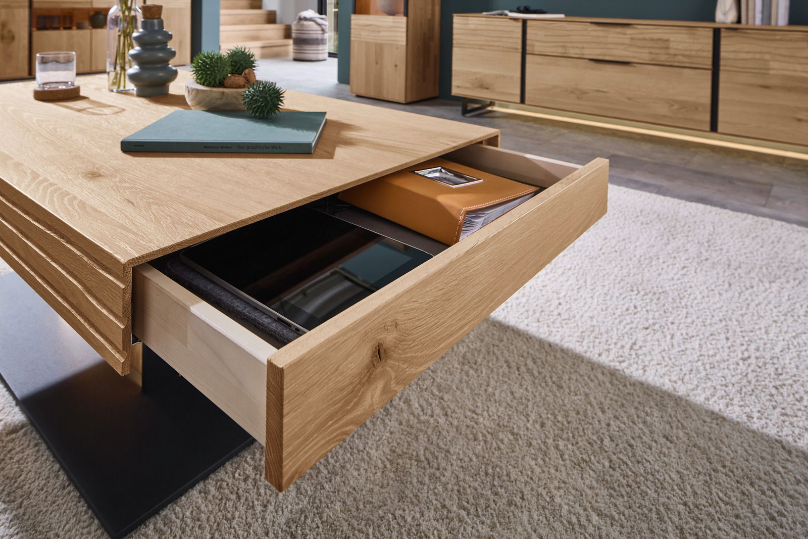 Moderner Couchtisch aus Holz mit Schublade, die von der Seite geöffnet ist, auf einem hellen Teppich.