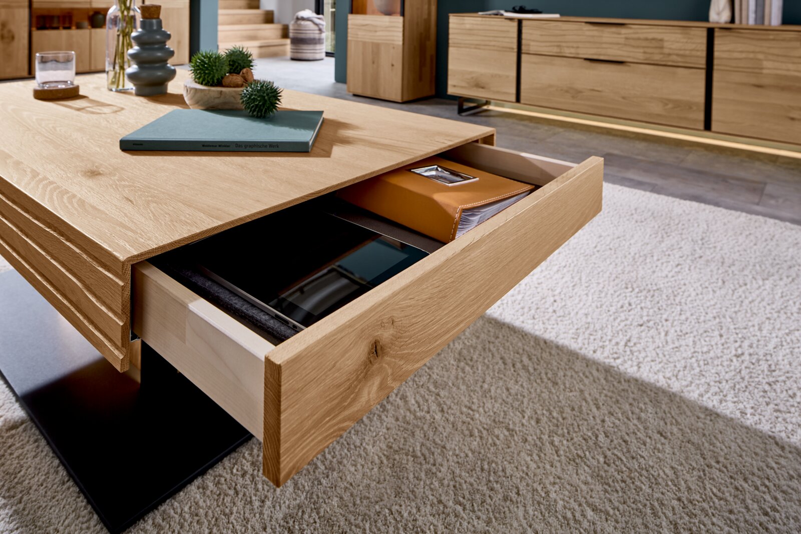 Moderner Couchtisch aus Holz mit Schublade, die von der Seite geöffnet ist, auf einem hellen Teppich.