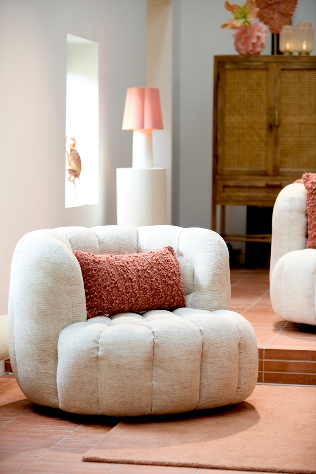 Light&Living Fauteuil AMARA Gezellige, crèmekleurige fauteuil met ronde vorm en een gestructureerd, roestkleurig kussen, gezien vanaf de zijkant.