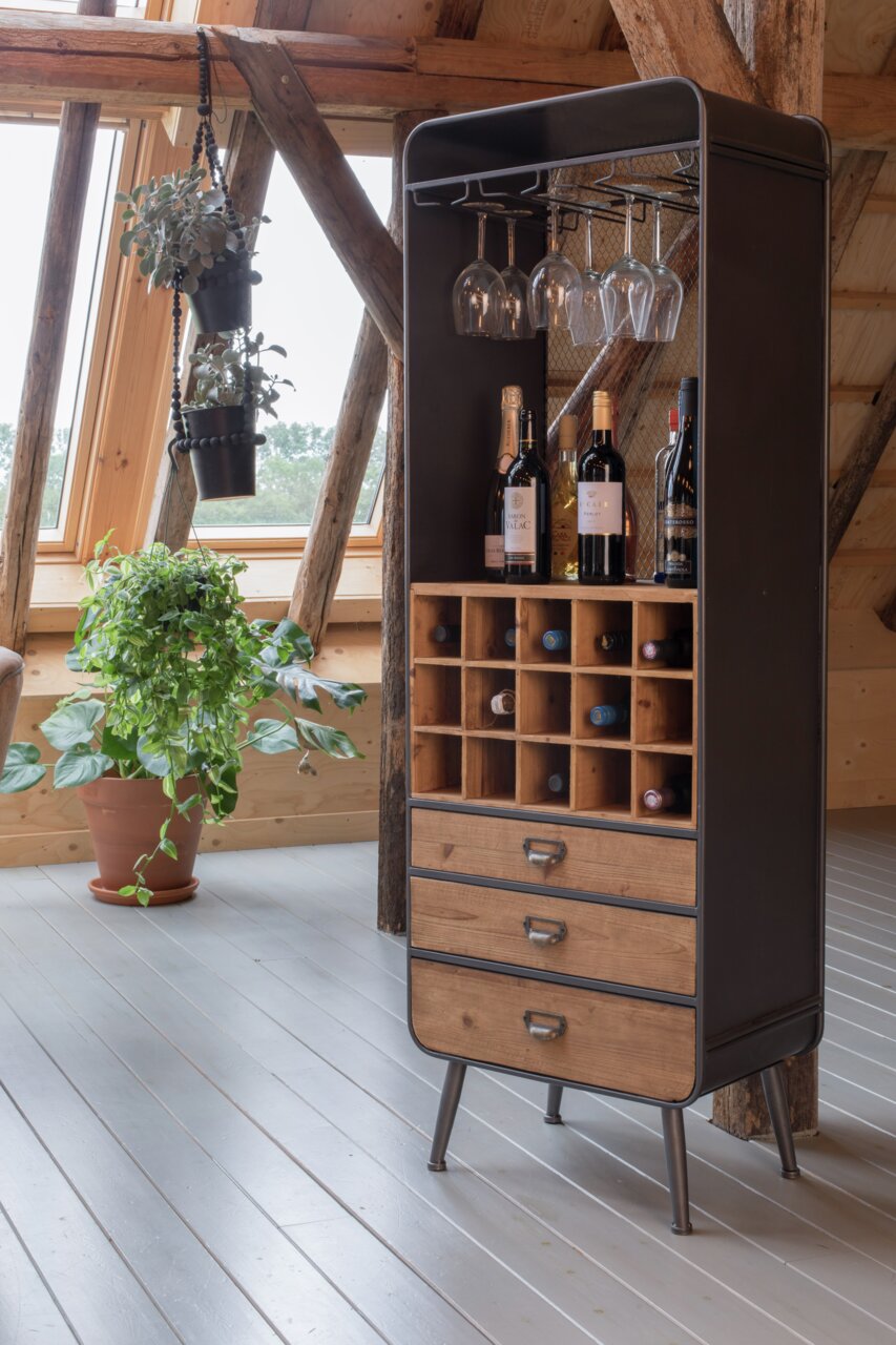 Weinregal aus Holz und Metall mit Flaschen- und Glashalterungen, frontal fotografiert in einem gemütlichen Raum mit Pflanzen.