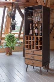 Weinregal aus Holz und Metall mit Flaschen- und Glashalterungen, frontal fotografiert in einem gemütlichen Raum mit Pflanzen.