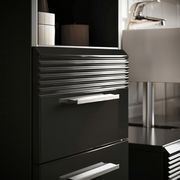 Nahaufnahme eines modernen, schwarzen Waschbeckenunterschranks mit gerillten Fronten und silbernen Griffen, seitliche Perspektive.