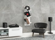 Weißes, wandmontiertes Vinyl-Schallplattenregal mit drei Ablagen und Schallplatten in modernem Wohnzimmer vor grauer Steinoptik-Wand, Frontansicht in leichter Schrägperspektive