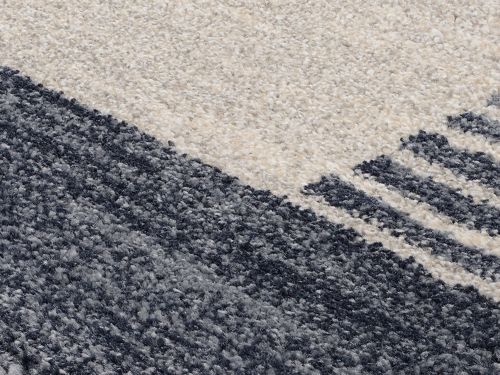 Nahaufnahme eines Frisé-Teppichs mit grauen und cremefarbenen Streifen, diagonale Perspektive.