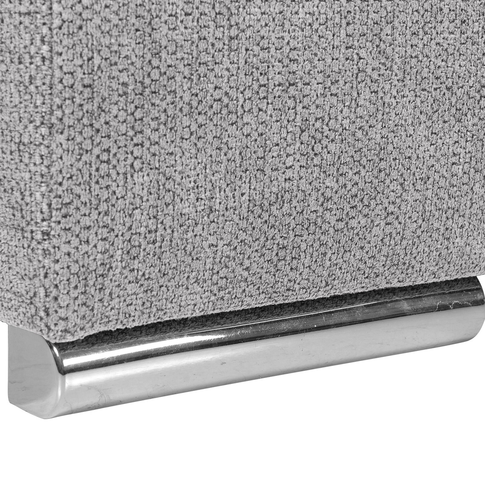 Nahaufnahme einer grauen, texturierten Stoffoberfläche mit einem glänzenden, metallischen Fuß.