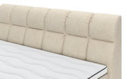 Nahaufnahme eines Boxspringbetts mit gestepptem, beige gestreiftem Kopfteil und weißer Matratze, seitliche Perspektive