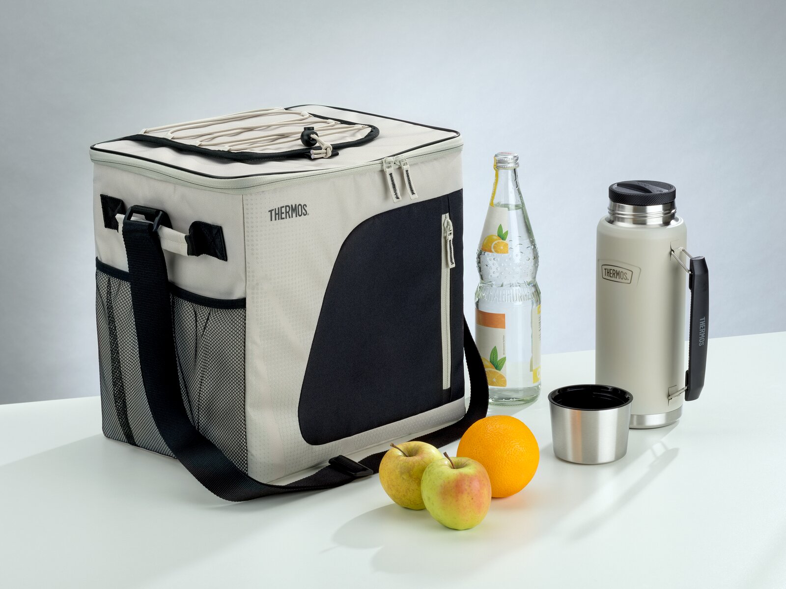Thermos Kühltasche in Beige und Schwarz mit Schultergurt, Thermosflasche, Trinkbecher, Wasserflasche und Obst, aus leicht erhöhter Frontalperspektive