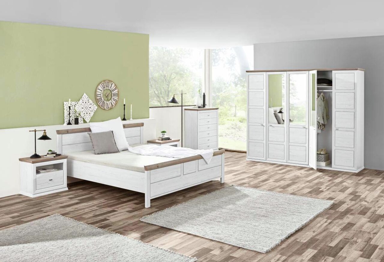 Schlafzimmer mit einem weißen Bett 140x200 cm, flankiert von zwei Nachttischen, in einem hellen Raum mit großen Fenstern, aus der Perspektive von vorne links.