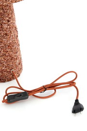 Detailansicht einer braun strukturierten Leuchte aus leicht erhöhter Seitenperspektive mit textilummanteltem Netzkabel, schwarzem Schnurschalter und Eurostecker.
