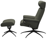 Seitliche Ansicht eines Einzelsessels mit Kopfstütze und passendem Fußhocker in dunkelgrünem Stoffbezug auf schwarzen Metallfüßen.