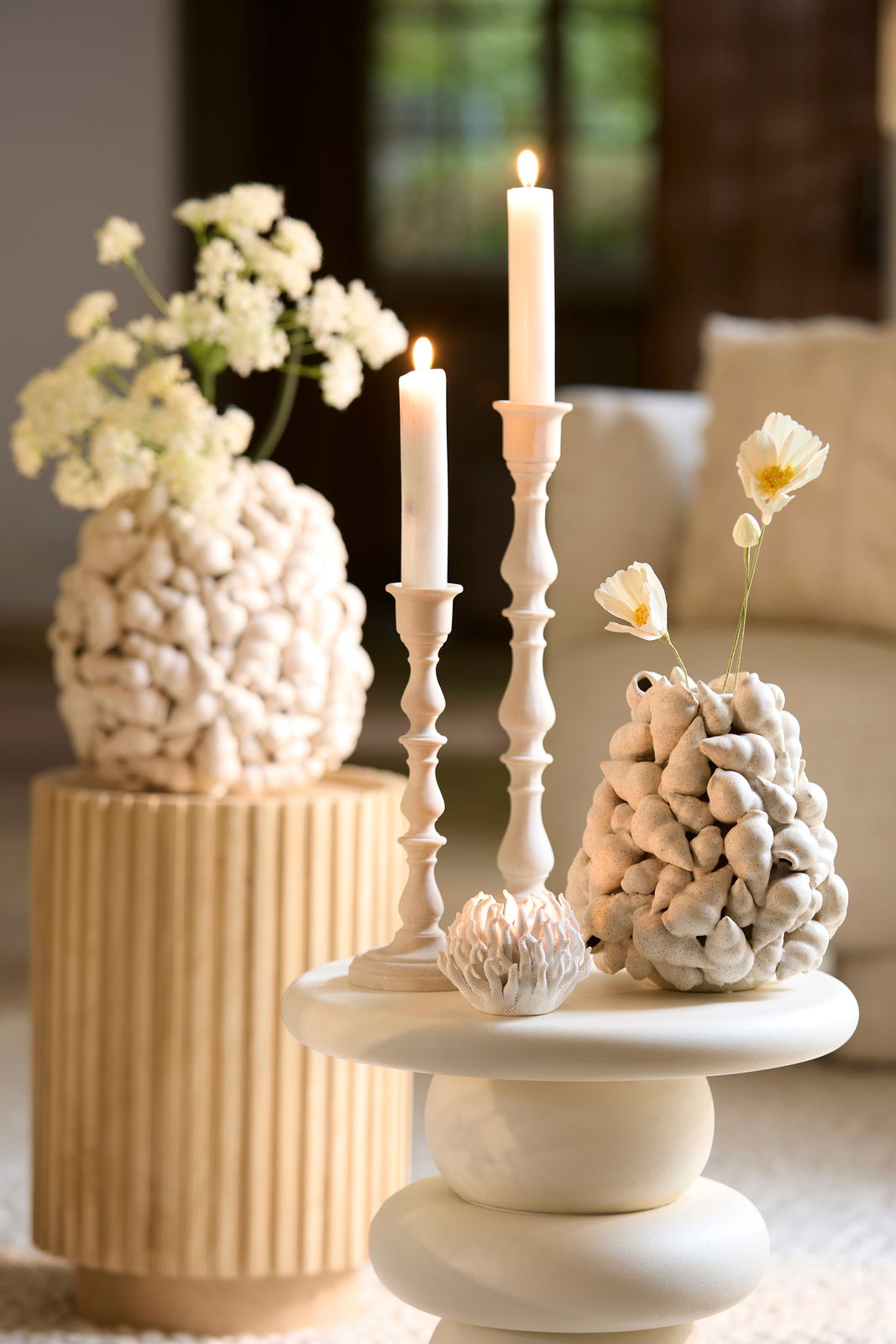 Nahaufnahme eines stilvollen Teelichthalters auf einem Tisch, umgeben von dekorativen Kerzen und Vasen in einem modernen Wohnambiente.