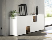Modernes weißes Sideboard mit glatten Fronten und zwei offenen Holz-Nischen, dekoriert mit Pflanze und Vasen, in einem hellen Wohnraum; Perspektive: frontale Ansicht leicht von links.
