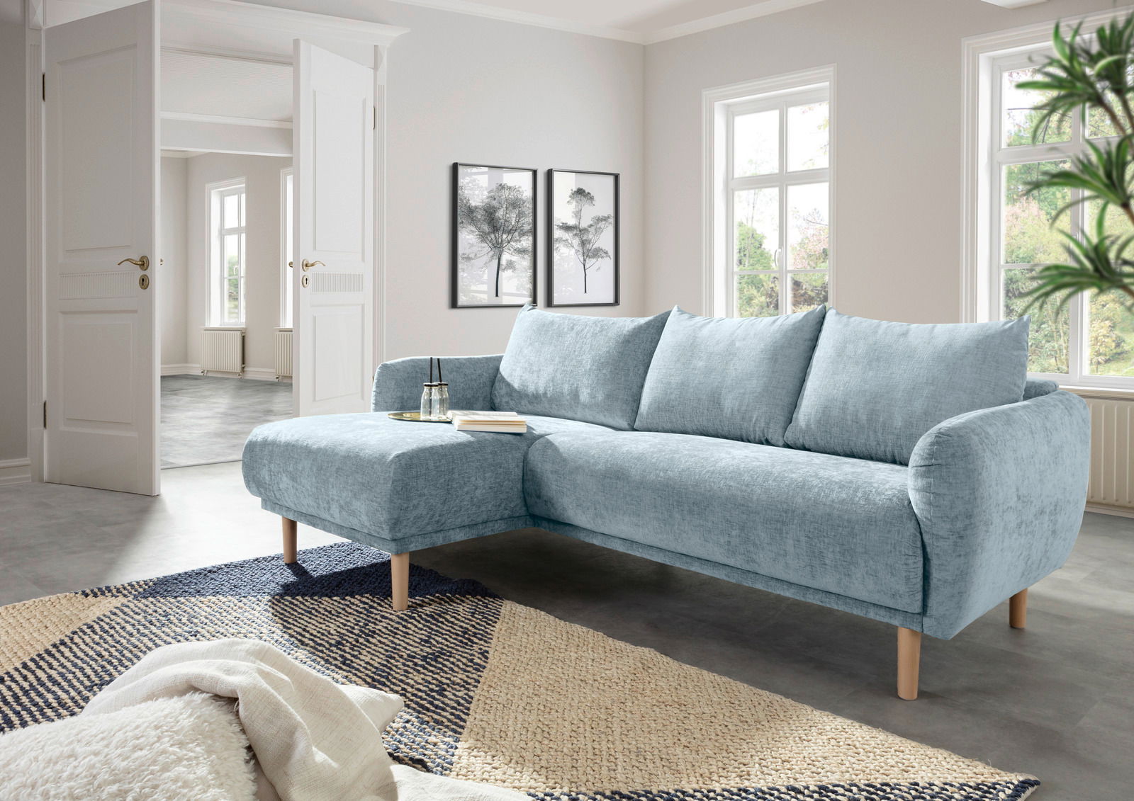 Helles, modernes Ecksofa mit Ottomane links in einem stilvollen Wohnzimmer, seitliche Perspektive.