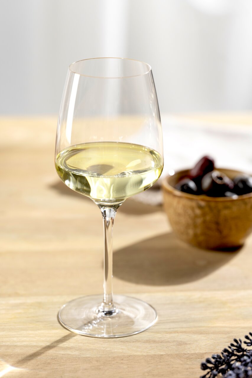 Leonardo Rieslingglas CESTI Elegant Rieslingglas met een inhoud van 280 ml, gevuld met witte wijn, op een tafel met een schaal olijven op de achtergrond, gezien vanuit de zijkant.