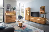 Moderne Wohnzimmermöbelkombination aus Holz mit LED-Beleuchtung, bestehend aus Highboard, Sideboard, Couchtisch und Wandregal, in einem hellen Raum mit großen Fenstern, seitliche Perspektive.