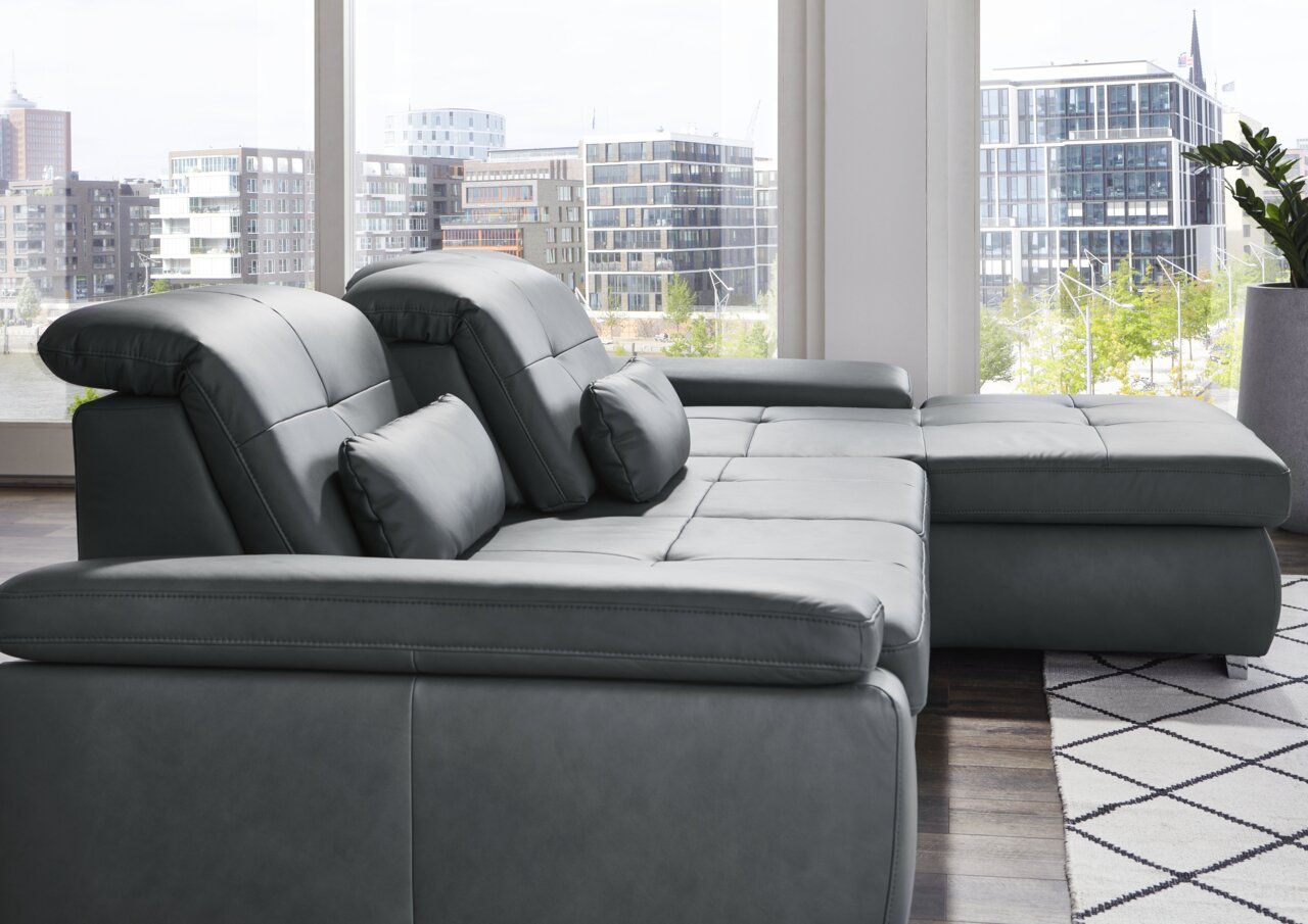 Moderne longchair-combinatie in donker leer, zijaanzicht met uitzicht op grote ramen en de stedelijke omgeving.