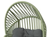 Nahaufnahme eines Gartensessels mit grünem Rattangeflecht und grauem Kissen, von oben betrachtet.