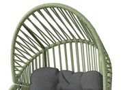 Nahaufnahme eines Gartensessels mit grünem Rattangeflecht und grauem Kissen, von oben betrachtet.