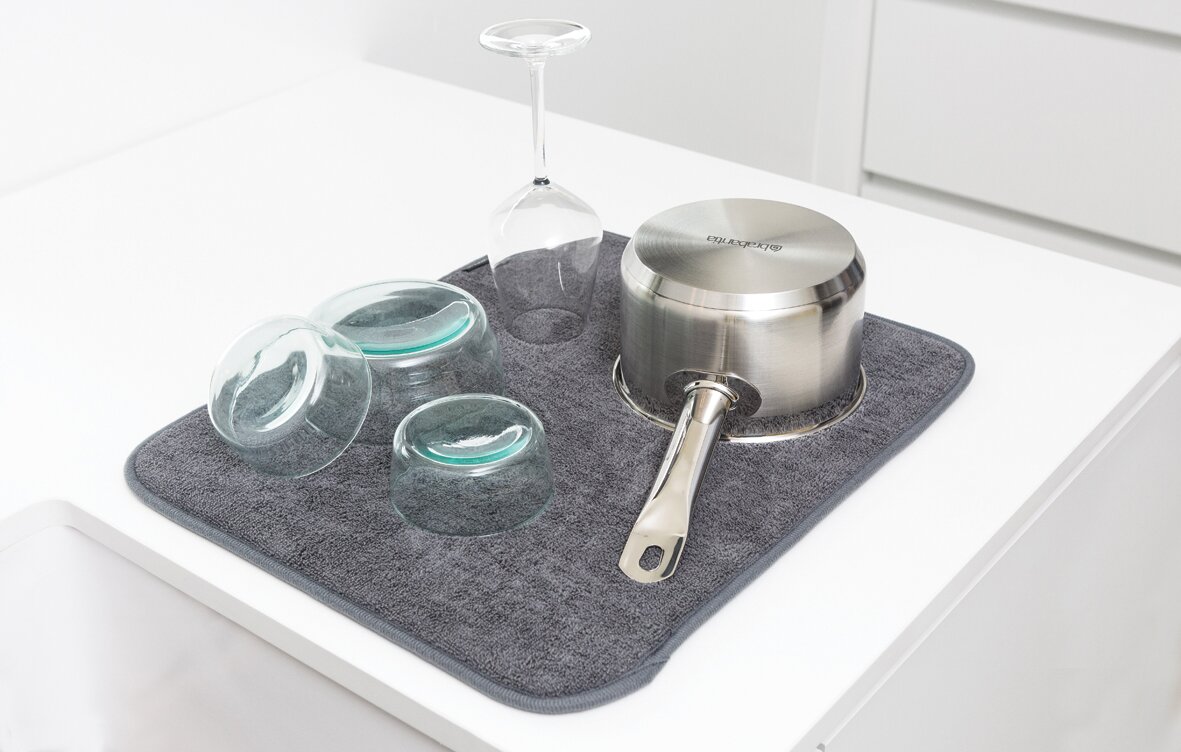 Brabantia Trockenmatte SINKSIDE Graue Trockenmatte auf einer weißen Arbeitsfläche, darauf stehen umgedrehte Gläser und ein Topf. Perspektive von oben.