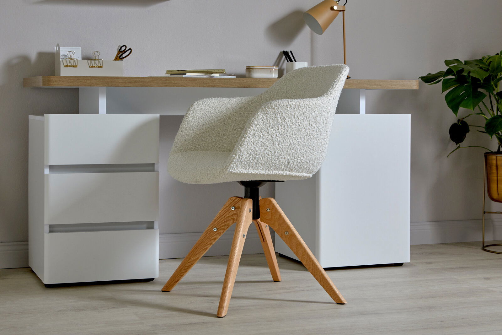 Jahnke Stuhl SHELL Moderner Stuhl mit weißem Bouclé-Stoffbezug und Holzbeinen, seitliche Perspektive vor einem Schreibtisch.