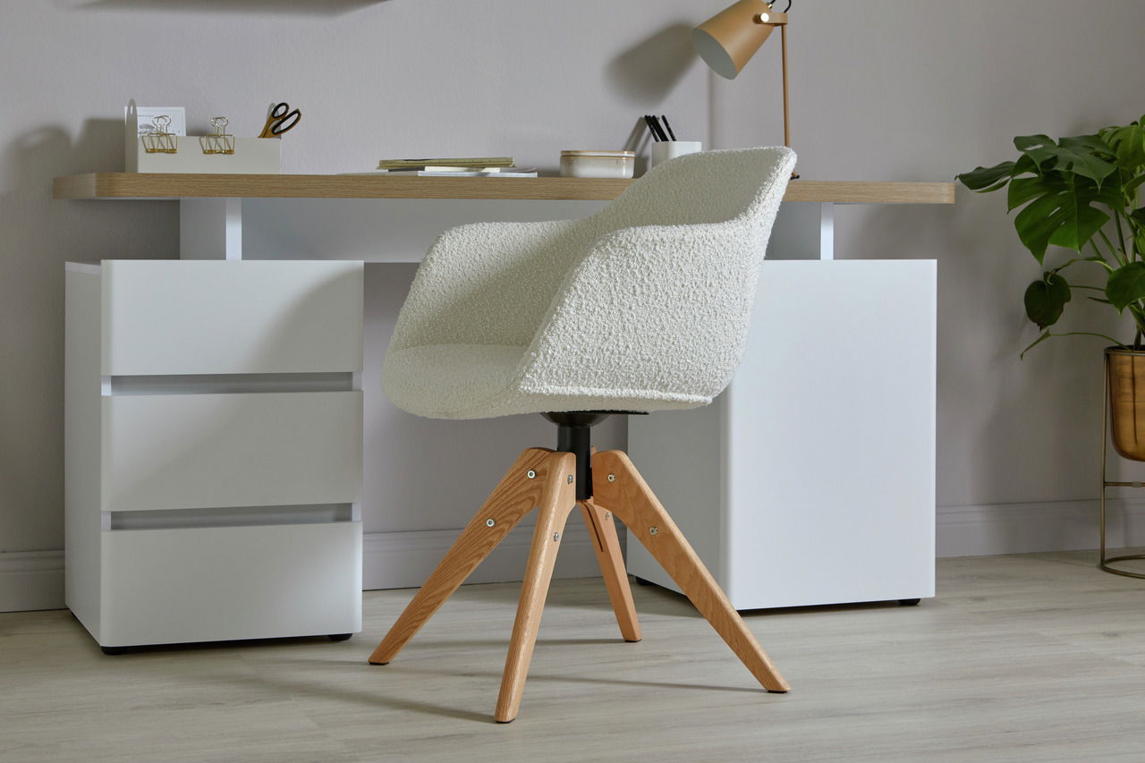 Moderner Stuhl mit weißem Bouclé-Stoffbezug und Holzbeinen, seitliche Perspektive vor einem Schreibtisch.