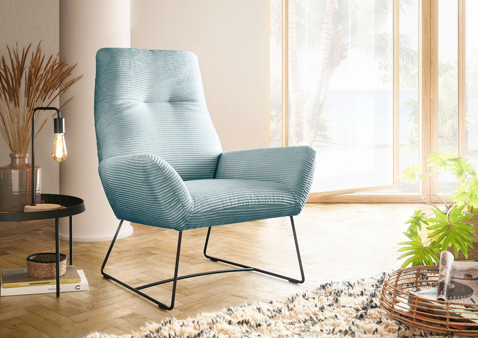 Moderner blauer Sessel mit geripptem Stoffbezug, seitliche Perspektive, in einem hellen Raum mit großen Fenstern und Holzboden.