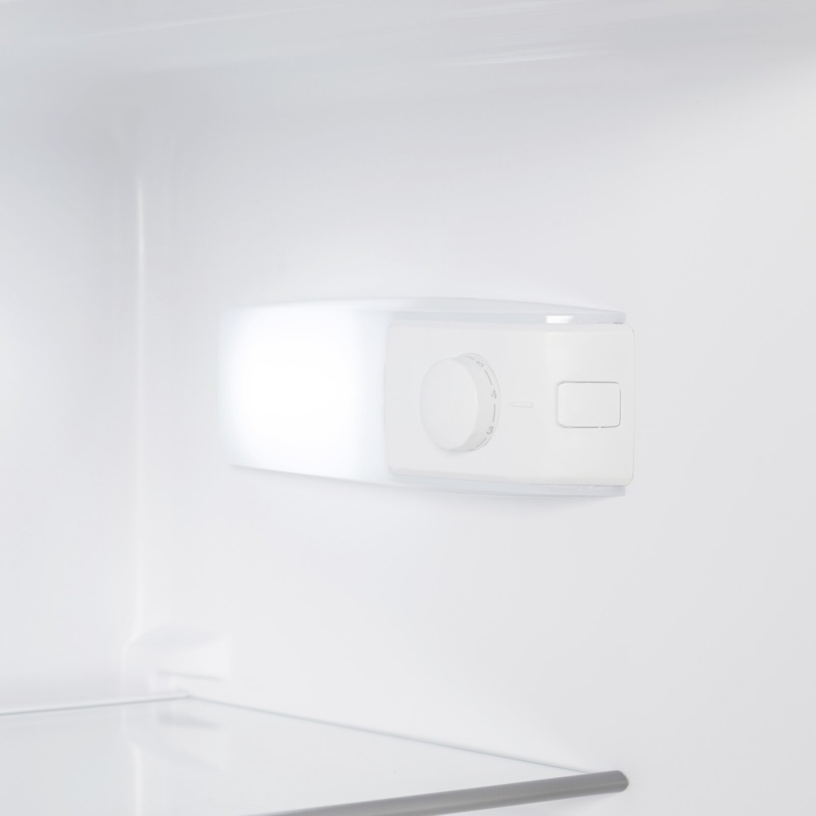 Weiße Kühlschrank-Innenansicht mit Thermostat-Drehregler und Schalter, Nahaufnahme von vorne rechts.