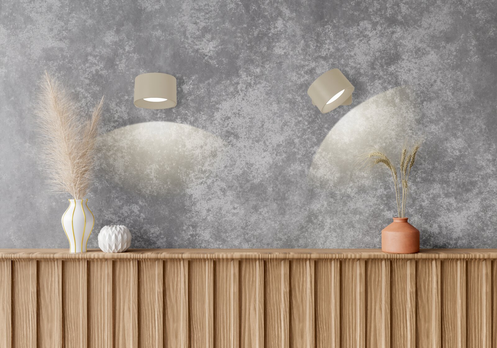 Zwei beige Wandstrahler auf grauer Strukturwand werfen weiche Lichtkegel über eine Holzkonsole mit Vasen und Trockenpflanzen, Frontansicht.