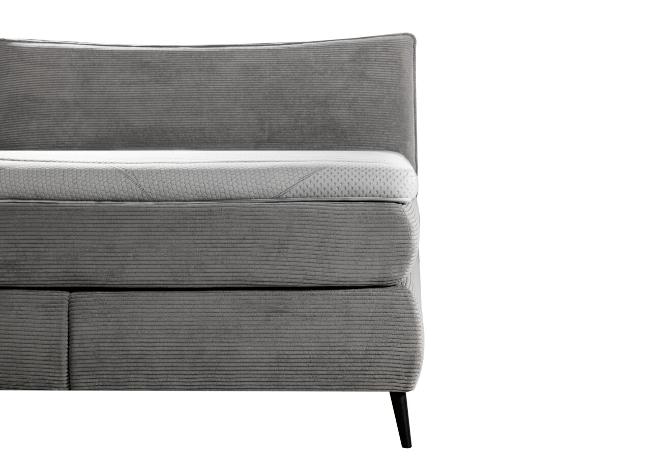 Seitliche Ansicht eines grauen Boxspringbetts mit gestepptem Kopfteil und modernen schwarzen Beinen.