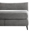 Seitliche Ansicht eines grauen Boxspringbetts mit gestepptem Kopfteil und modernen schwarzen Beinen.