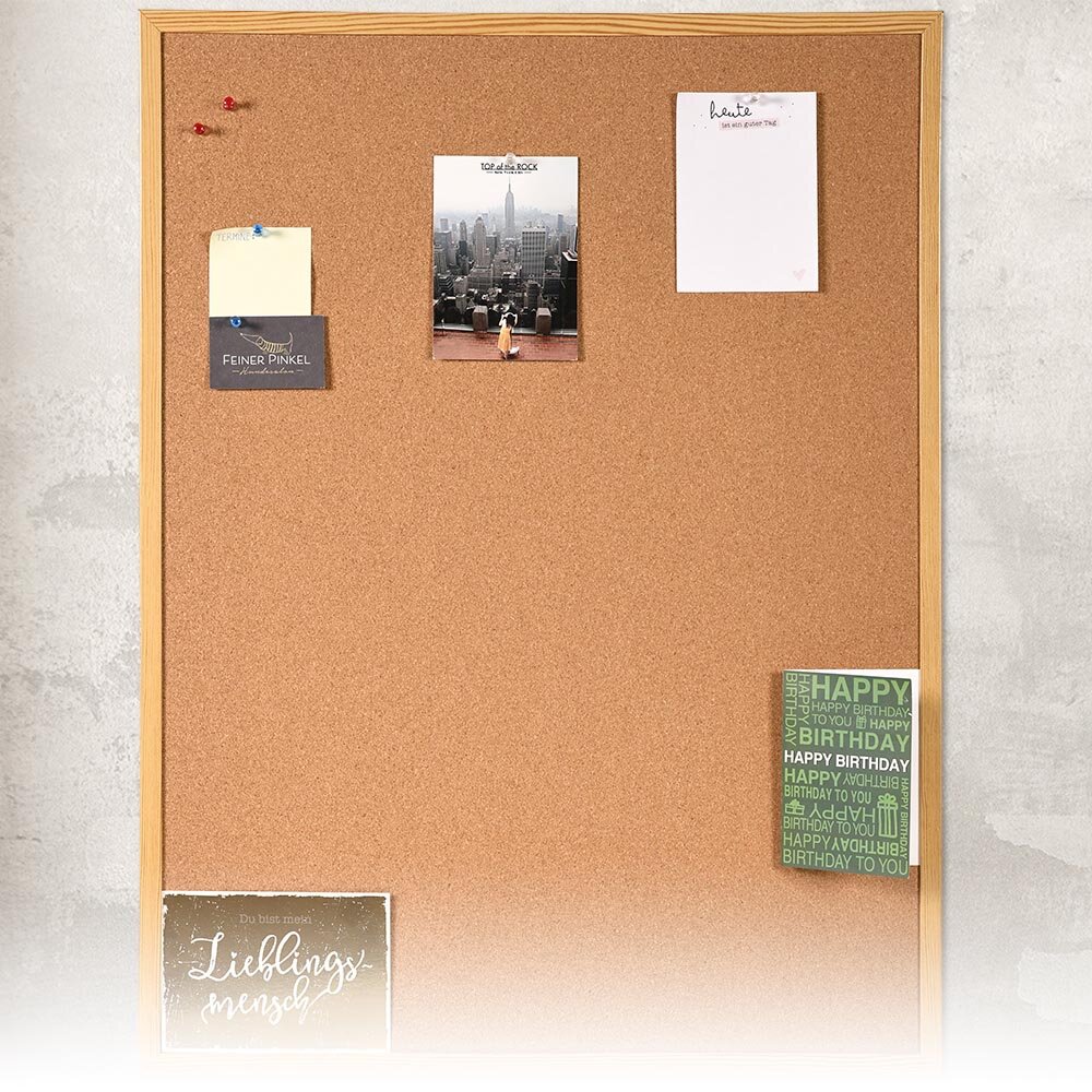 Kork-Pinnwand mit Holzrahmen, dekoriert mit verschiedenen Notizen und Karten, frontal fotografiert.