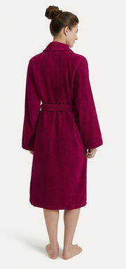 Rückansicht eines weinroten Bademantels mit Schalkragen, getragen von einer Person. Der Bademantel hat lange Ärmel und einen Gürtel.