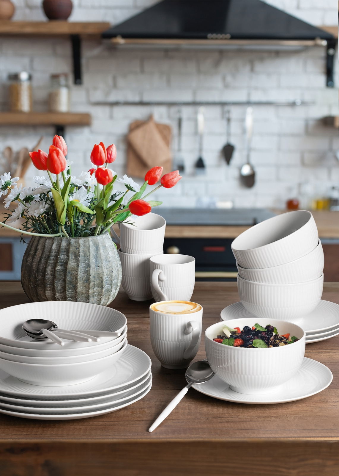 Kombiservice 30-teilig in einer modernen Küche, bestehend aus weißen Tellern, Schalen und Tassen, mit einem Blumenarrangement im Hintergrund. Perspektive: Frontalansicht auf das Geschirrset.