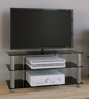 Schwarzes TV- und HiFi-Rack mit Glasböden und Metallbeinen, darauf ein Flachbildfernseher sowie darunter zwei silberne Recorder und ein Verstärker; Frontalansicht aus leicht erhöhter Perspektive.